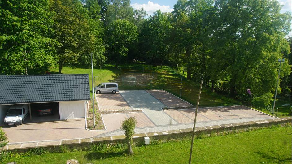 Ansicht Parkplatz und Doppelcarport mit Doppelgarage aus Richtung Kirche 